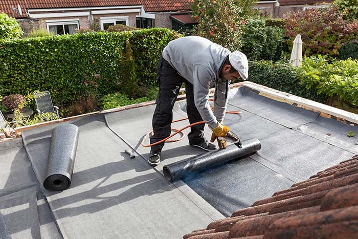 Roofer installing coating on flat roof in Denver, CO