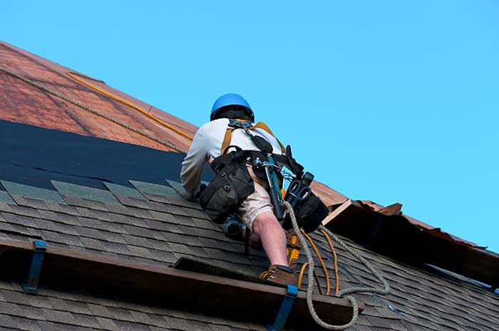 Worker installing asphalt shingle in Denver