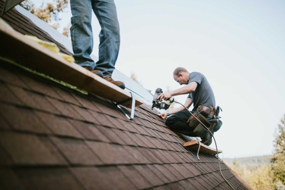 A worker installing asphalt shingle roof on a house in Denver, CO
